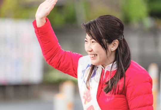 街頭で手を振り挨拶する池田あやのの写真